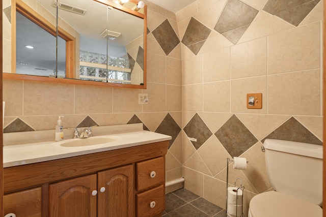 bathroom featuring vanity, toilet, tile walls, and tasteful backsplash