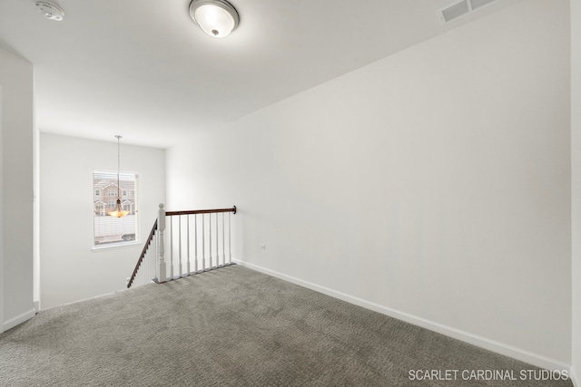 carpeted spare room featuring a chandelier