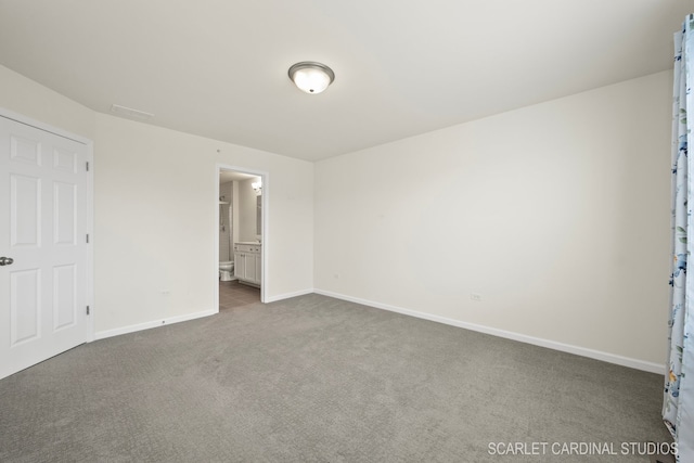 unfurnished bedroom with dark carpet and connected bathroom