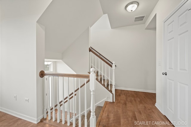 stairway with hardwood / wood-style floors and lofted ceiling