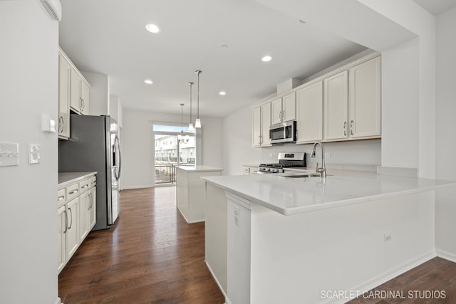 kitchen featuring kitchen peninsula, white cabinetry, pendant lighting, and appliances with stainless steel finishes