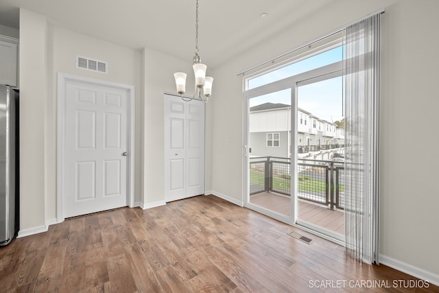 unfurnished dining area with hardwood / wood-style floors and a chandelier