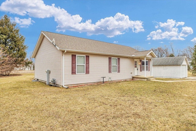 ranch-style home featuring an outbuilding, a front lawn, and roof with shingles