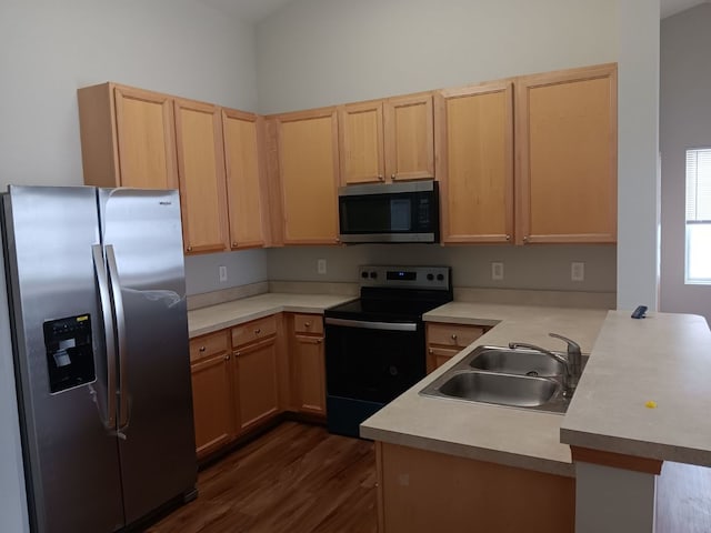 kitchen featuring kitchen peninsula, appliances with stainless steel finishes, light brown cabinetry, dark wood-type flooring, and sink