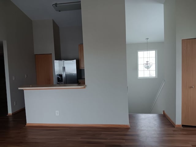 kitchen featuring decorative light fixtures, stainless steel fridge, kitchen peninsula, and dark wood-type flooring