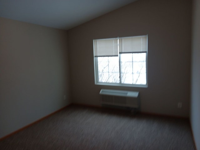 unfurnished room featuring vaulted ceiling and dark carpet