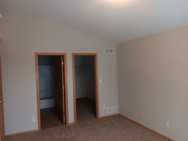 unfurnished bedroom featuring carpet floors, a spacious closet, a closet, and lofted ceiling