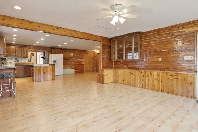 living room with wooden walls, light hardwood / wood-style flooring, ceiling fan, and sink