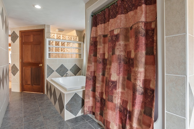 interior space with tile patterned floors, a relaxing tiled tub, and tile walls