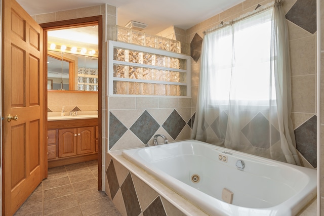 bathroom featuring tile patterned floors, a relaxing tiled tub, tile walls, and vanity