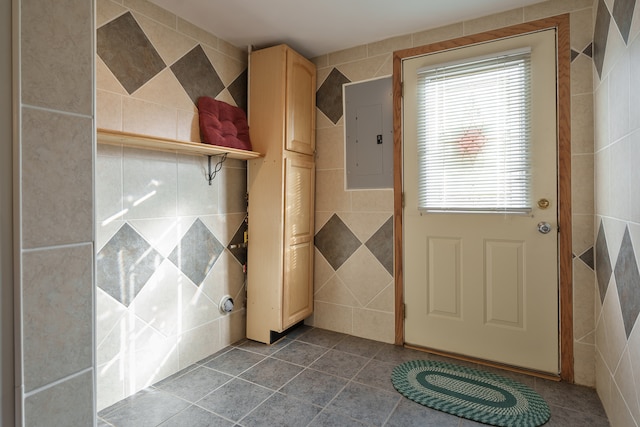 doorway to outside with electric panel, tile patterned flooring, and tile walls