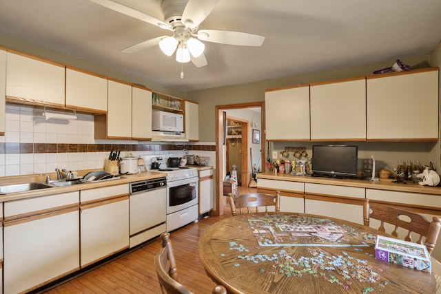 kitchen with tasteful backsplash, white appliances, ceiling fan, sink, and light hardwood / wood-style flooring