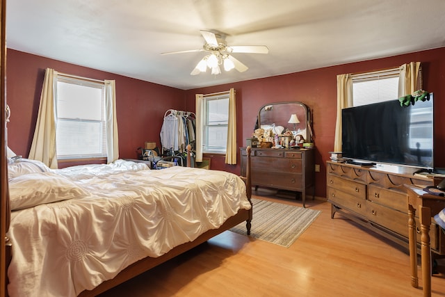 bedroom featuring multiple windows, hardwood / wood-style floors, and ceiling fan