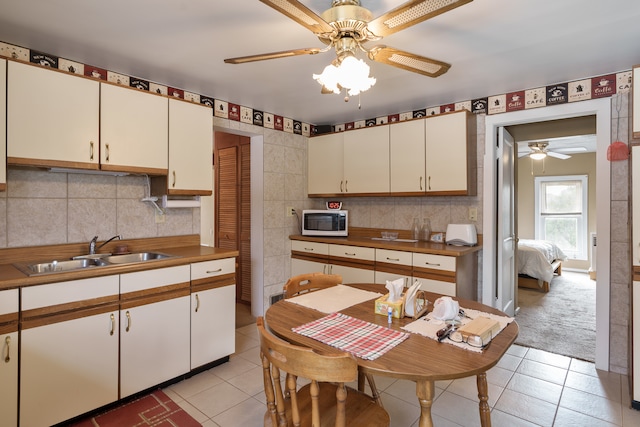 kitchen featuring light tile patterned floors, ceiling fan, and sink