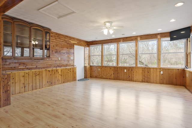 interior space with light hardwood / wood-style floors, plenty of natural light, wooden walls, and ceiling fan