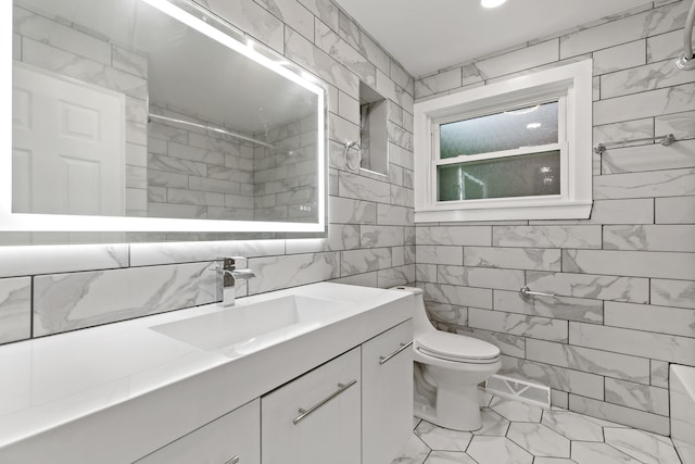 bathroom with vanity, toilet, tile walls, and a tile shower