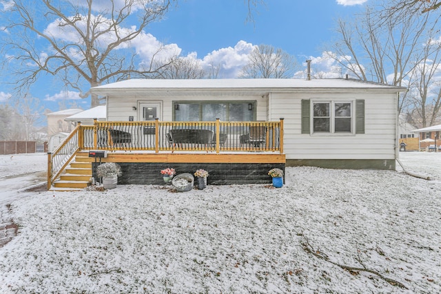 snow covered house with a wooden deck