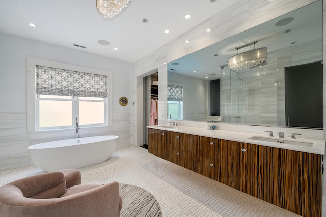 bathroom featuring vanity, an inviting chandelier, and tile walls