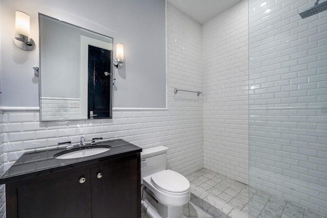 bathroom with vanity, toilet, tile walls, and a tile shower