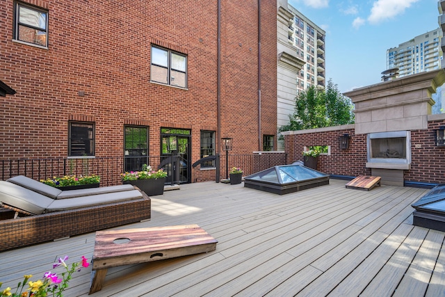 wooden deck with a jacuzzi and an outdoor fireplace