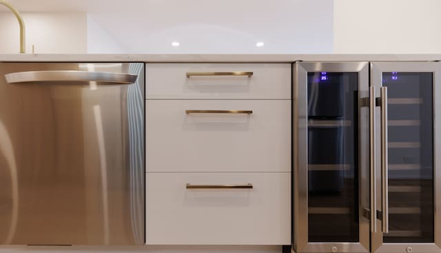 details with dishwasher, white cabinetry, and beverage cooler