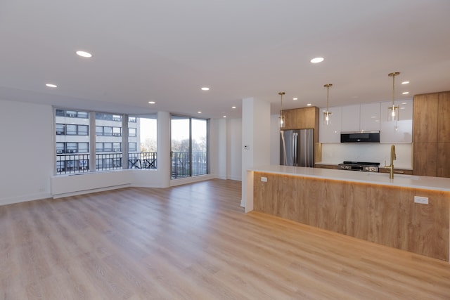 kitchen featuring sink, hanging light fixtures, light wood-type flooring, white cabinetry, and stainless steel appliances