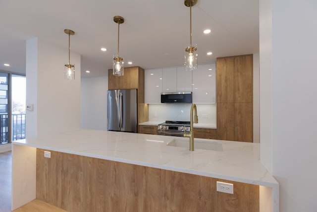 kitchen featuring light stone countertops, kitchen peninsula, stainless steel appliances, and white cabinetry