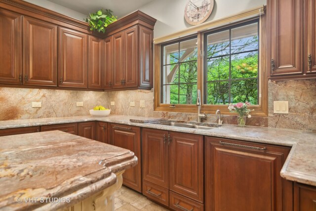 kitchen with light stone counters, sink, and tasteful backsplash