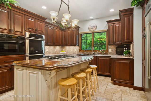 kitchen with stainless steel appliances, a chandelier, a kitchen bar, decorative backsplash, and a kitchen island