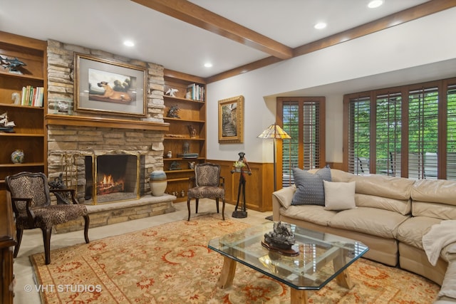 living room featuring beam ceiling, a stone fireplace, and wood walls