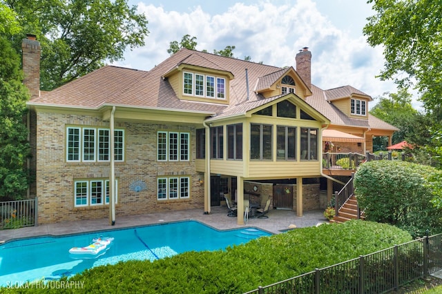 rear view of property featuring a fenced in pool, a patio area, and a sunroom