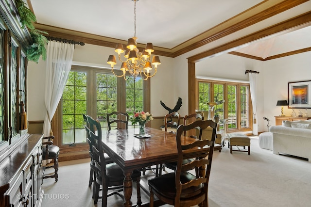 carpeted dining space with a notable chandelier, ornamental molding, a wealth of natural light, and french doors