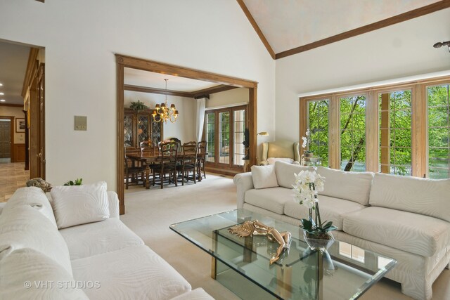 carpeted living room featuring a notable chandelier and high vaulted ceiling