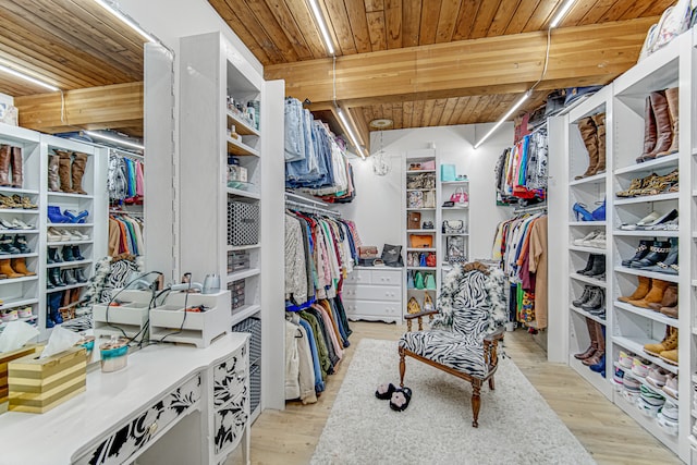 spacious closet with beamed ceiling and light wood-type flooring