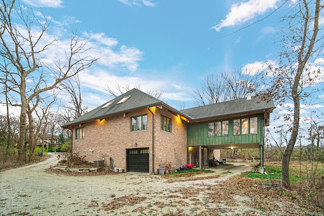 rear view of house with central AC, a garage, and a carport