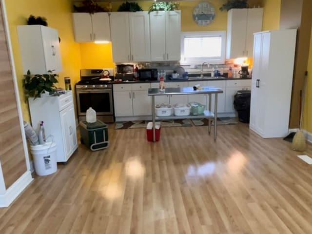 kitchen with light hardwood / wood-style flooring, white cabinetry, and white gas range