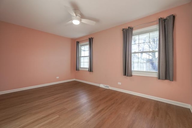 unfurnished room with a wealth of natural light, dark hardwood / wood-style floors, and ceiling fan