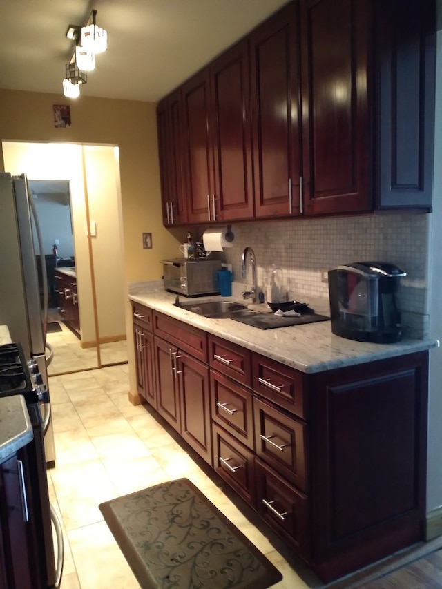 kitchen featuring light stone countertops, sink, stove, white fridge, and decorative backsplash