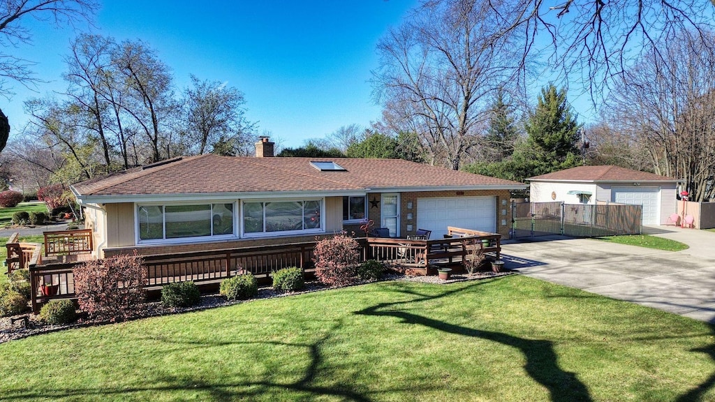 single story home featuring a garage, an outbuilding, a wooden deck, and a front lawn