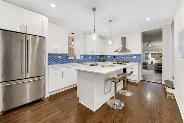 kitchen featuring dark hardwood / wood-style flooring, white cabinetry, high end fridge, and wall chimney exhaust hood