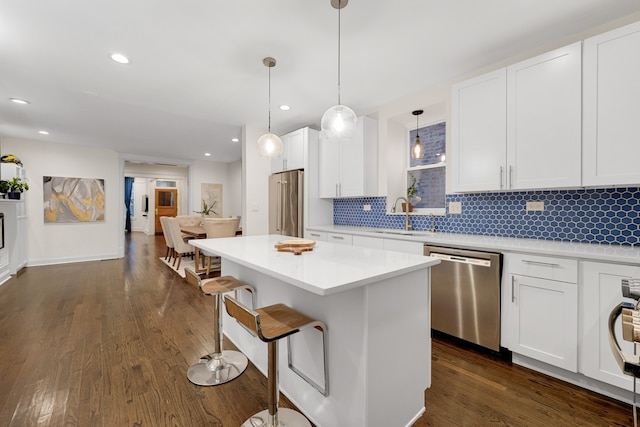 kitchen featuring stainless steel appliances, sink, decorative light fixtures, dark hardwood / wood-style floors, and white cabinetry