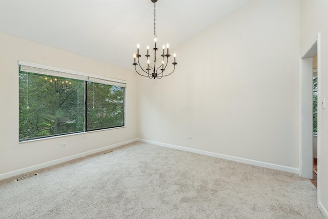 spare room featuring carpet, a chandelier, and lofted ceiling