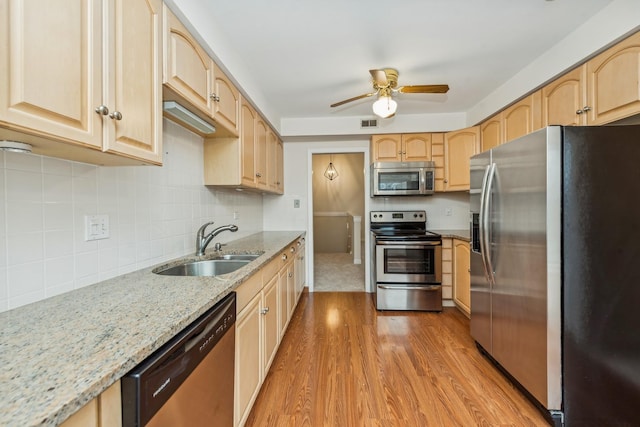 kitchen with appliances with stainless steel finishes, light wood-type flooring, light brown cabinetry, ceiling fan, and sink