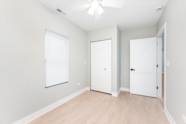 unfurnished bedroom with ceiling fan, light wood-type flooring, and a closet