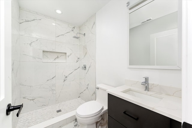 bathroom with vanity, toilet, and a tile shower