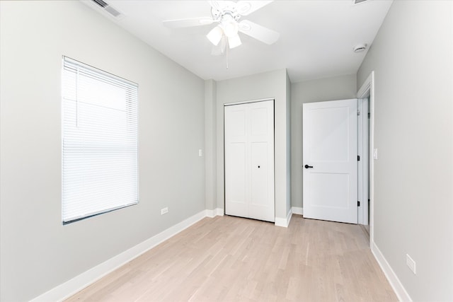 unfurnished bedroom with ceiling fan, light wood-type flooring, and a closet