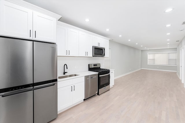 kitchen featuring appliances with stainless steel finishes, light hardwood / wood-style flooring, and white cabinetry