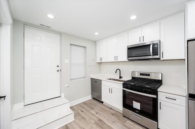 kitchen featuring white cabinetry, sink, stainless steel appliances, and light hardwood / wood-style floors