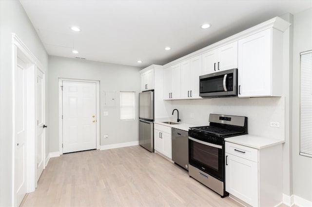 kitchen featuring appliances with stainless steel finishes, light hardwood / wood-style flooring, white cabinetry, and sink