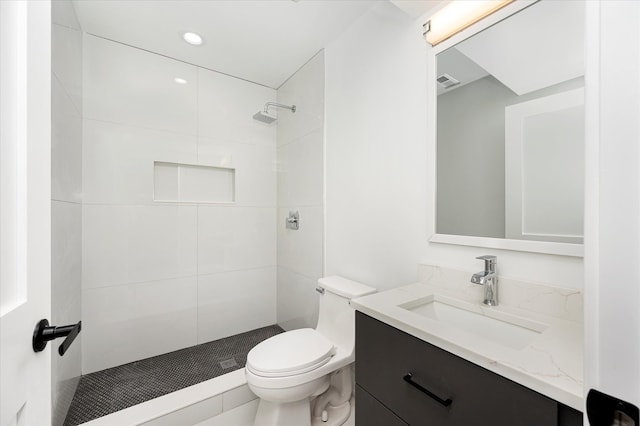 bathroom featuring tiled shower, vanity, and toilet